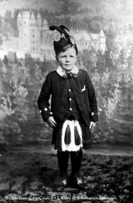 Studio portrait of a small boy wearing Highland dress.