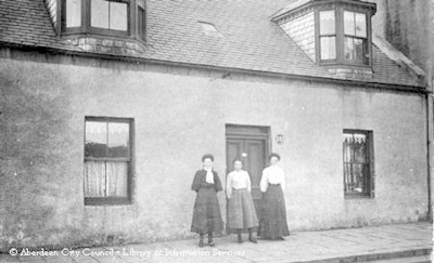 Three ladies outside front door of cottage