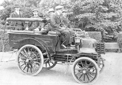 Five men sit in an early motor bus