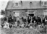Farm hands and family with plough horses posed outside farm house