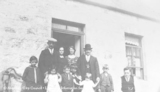 Group portrait of family posed outside front door of house