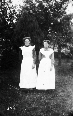 Portait of 2 women - domestic servants - in garden.